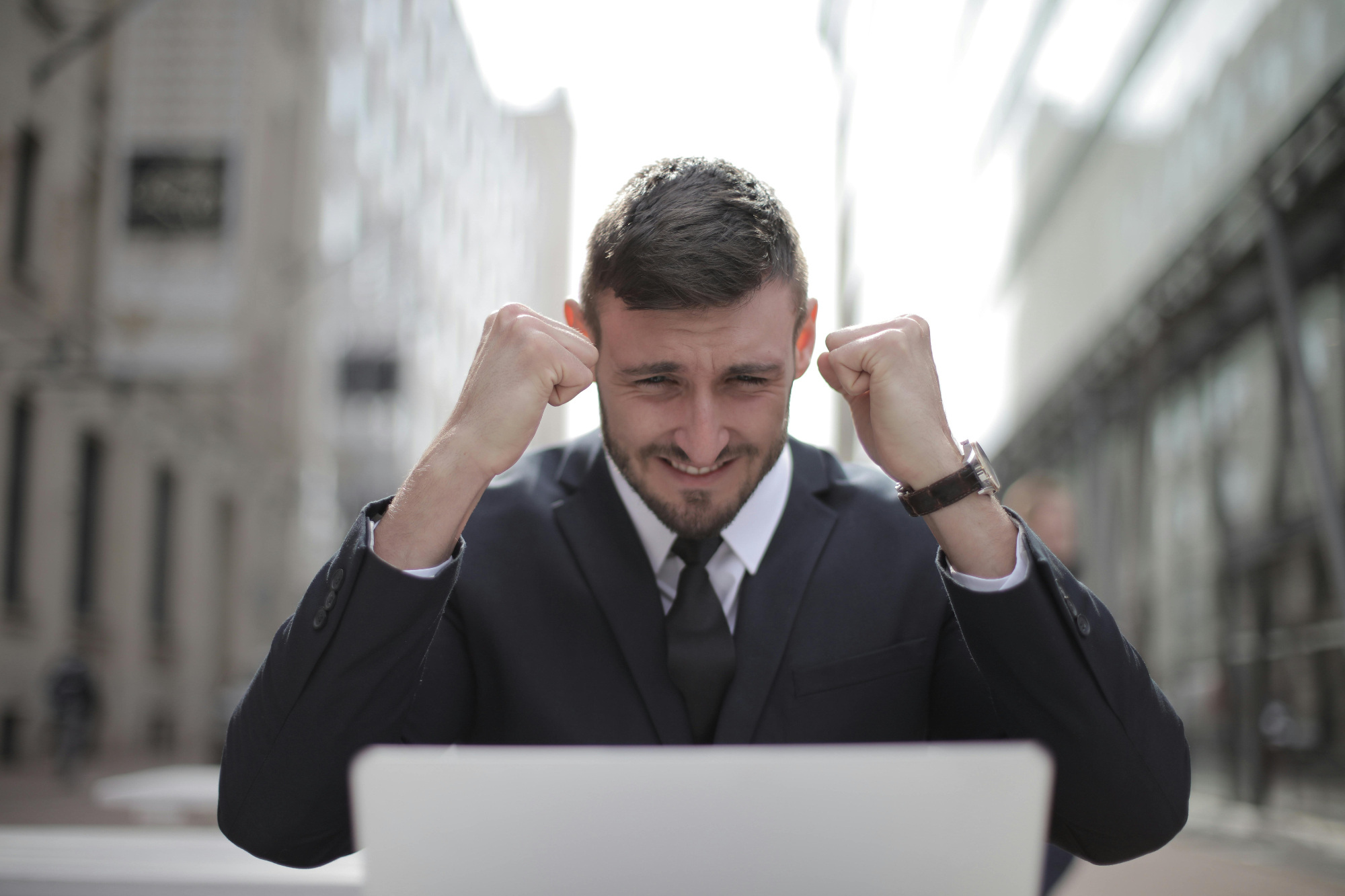 Man in suit celebrating in front of laptop.