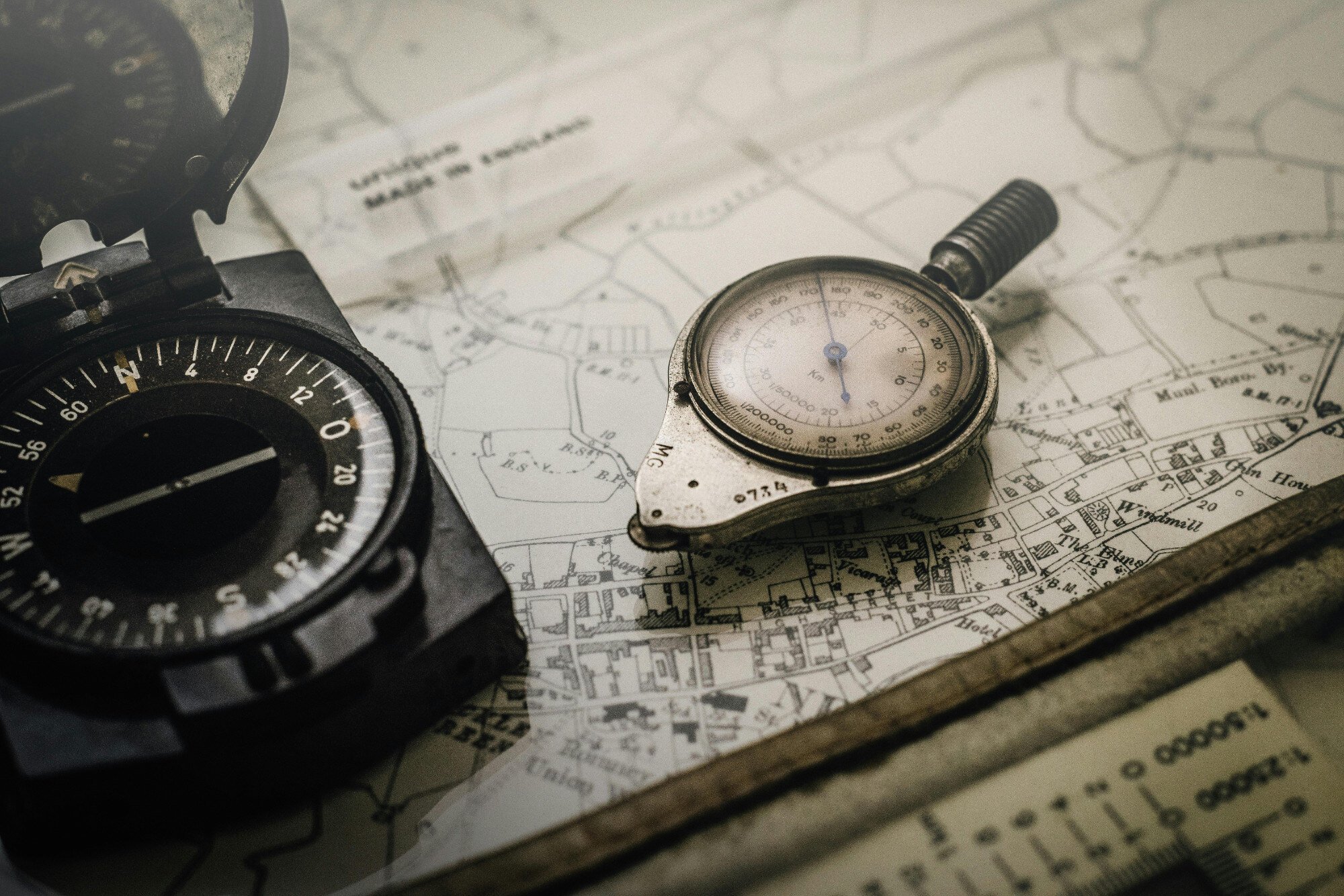 An old-looking compass sitting on an old map.