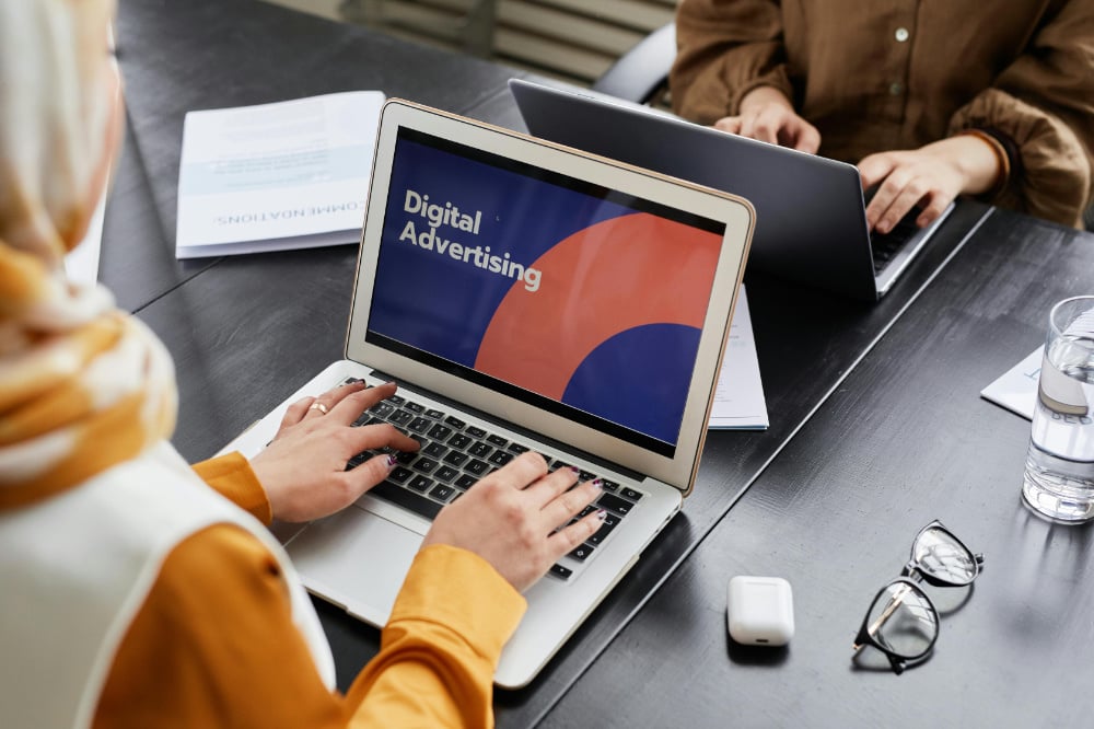 Laptop screen on office desk with digital advertising written on screen.