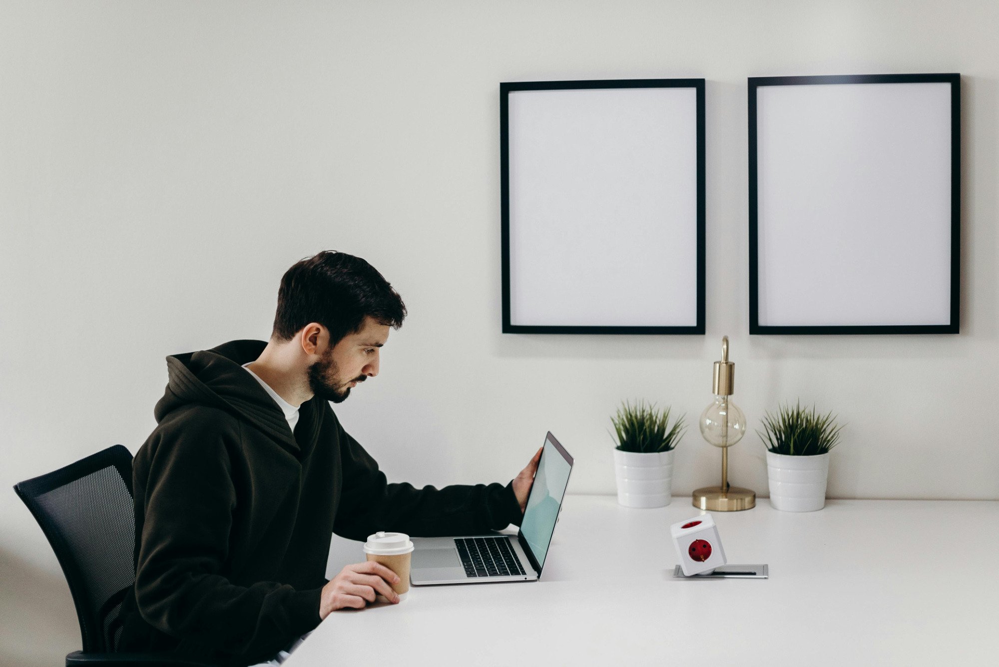 Freelancer sitting at desk with coffee in hand and laptop open.