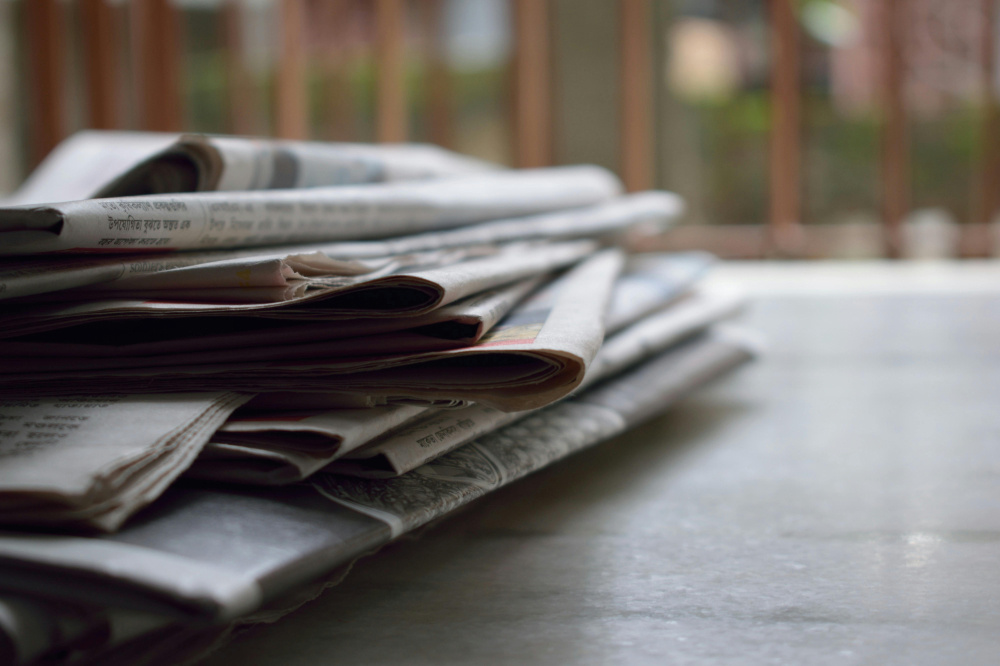 Stack of newspapers on wooden table.