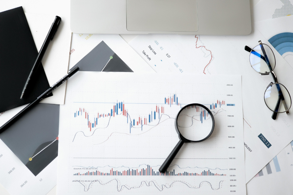 Various charts on a desk with magnifying glass on top.