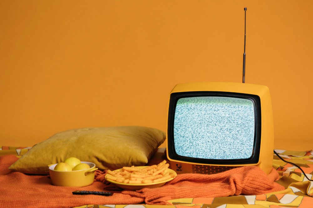 Yellow old-fashioned television on yellow bed surrounded by yellow items.